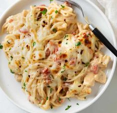 a white plate topped with pasta and meat covered in sauce, garnished with parsley