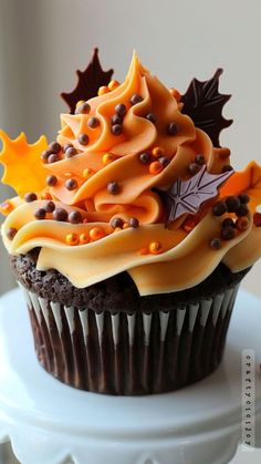 a cupcake decorated with orange and brown icing on top of a white plate