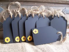 small tags with sunflowers are hanging from twine