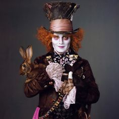 a man dressed in costume holding a rabbit and wearing a top hat with red hair