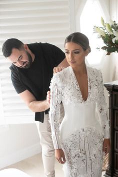 a man standing next to a woman in a white dress on top of a bed