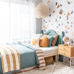 a bed room with a neatly made bed next to a window and a striped rug