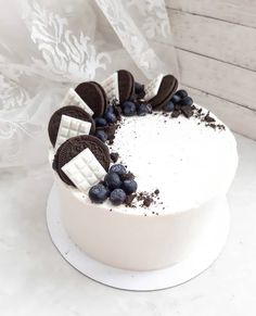 a white cake topped with cookies and blueberries