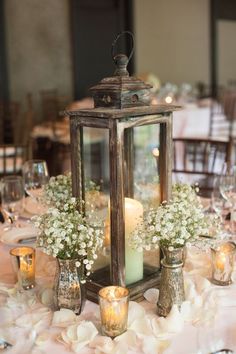 a lantern is sitting on top of a table with flowers and candles