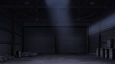 an empty warehouse with several barrels in the floor and one light shining on the wall