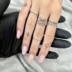 a woman's hand with three different tattoos on her fingers and one has a bow