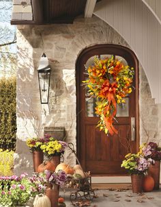 a front door decorated for fall with pumpkins and flowers