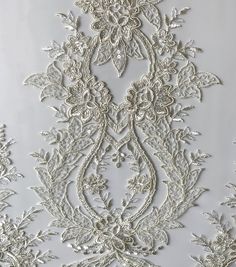 an embroidered fabric with white flowers and leaves on the bottom, in shades of grey