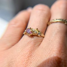 a woman's hand with a gold ring and two different colored stones on it