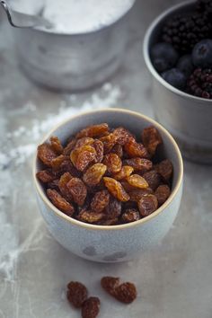 a bowl filled with raisins and blueberries next to another bowl full of raisins