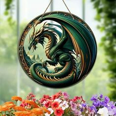 a green and yellow dragon hanging from a metal hook with flowers in the foreground