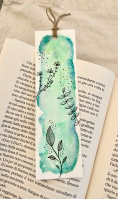 an open book with a watercolor painting on it and a tag hanging from the pages