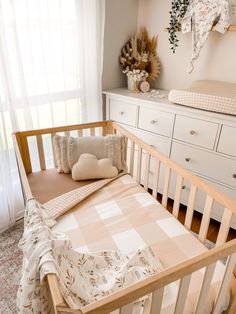 a baby's crib in the corner of a room with white dressers