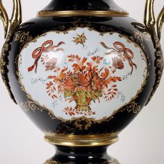 an ornate vase with gold trimmings and painted flowers on it's sides