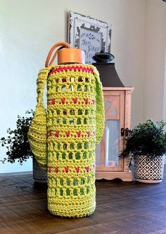 a crocheted green bag sitting on top of a wooden table next to a potted plant