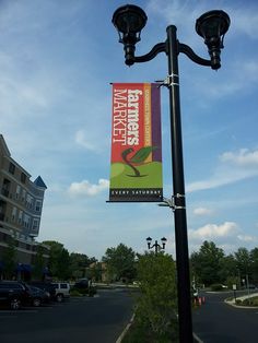 a street light with a banner hanging from it's side next to a parking lot