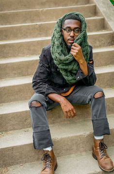 a man sitting on some steps with his hand under his chin and wearing a scarf over his head