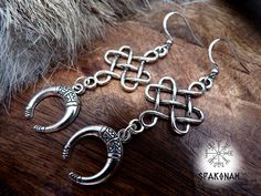 a pair of silver earrings sitting on top of a wooden table next to a fur