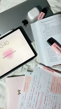 an open laptop computer sitting on top of a bed next to pink and white sheets