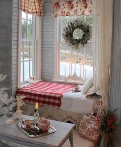 a bedroom decorated for christmas with a bed and table in front of the window, wreaths on the windowsill