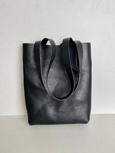 Beautiful,black leather tote. This Black leather tote bag is so strong and study can be worn by just about anyone. Black leather bag, in a beautiful natural black color leather. Simple and stylish. Black cowhide, thick and sturdy, and strong leather straps in  black leather. Raw finish to appreciate this beautiful leather. This bag is made with hand stichig  which makes a more solid and strong bag . Will wear in perfectly time.  A bit elegant and stylish black leather tote. Black leather tote,measures: (approx) 40cm wide  39 cm high Black Leather Minimalist Bucket Bag, Minimalist Black Leather Bucket Bag, Minimalist Black Bucket Bag, Black Minimalist Everyday Shoulder Bag, Black Minimalist Daily Shoulder Bag, Black Everyday Minimalist Shoulder Bag, Black Bucket Bag With Smooth Grain, Black Leather Bucket Bag With Smooth Grain, Black Leather Handle Bucket Bag For Daily Use