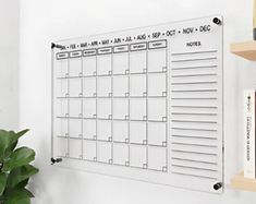 a whiteboard mounted to the wall with calendars on it and bookshelves