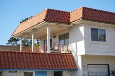 an apartment building with two balconies on the second floor and a red tiled roof