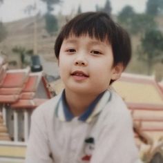 a young boy standing in front of a building with red roof tiles on it's sides