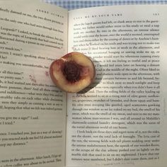 an open book with a piece of fruit sitting on it's side in front of the pages