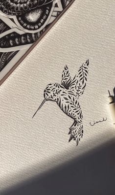 an ink drawing of a bird on paper next to a pen and inking pad