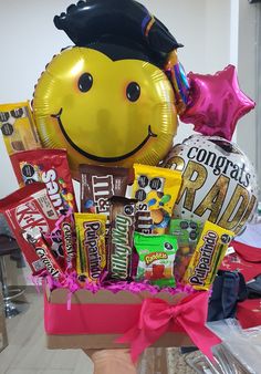 a box filled with candy and balloons in the shape of a smiley face