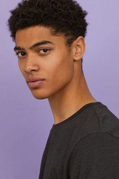 a young man wearing a black t - shirt looking at the camera