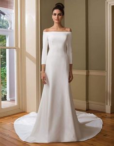 a woman in a white wedding dress standing on a wooden floor next to a window