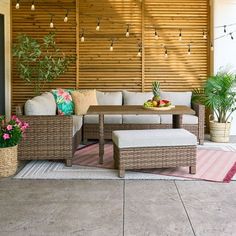 an outdoor living area with wicker furniture and potted plants on the side wall