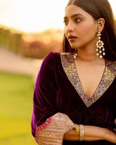 a woman in a purple dress and gold jewelry