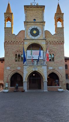 an old brick building with two towers and flags on it's front entrance area