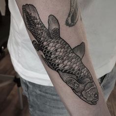 a black and white fish tattoo on the arm