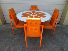 an orange and white table with four chairs next to a garage door on the sidewalk