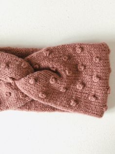 a close up of a knitted headband on a white surface