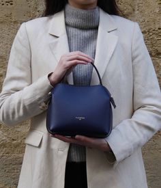 The Mini Swann bag in Midnight Blue, crafted from smooth calf leather, is a refined piece that perfectly complements a variety of outfits, whether they are simple or more colorful. Its compact size is ideal for carrying your essentials while maintaining an elegant and discreet form.
It elegantly matches with neutral shades such as white, beige, or grey for a classic style. For a bolder note, pair it with vibrant colors like brick red or burnt orange. In summer, pastel hues are a refreshing choi Swan Bag, Navy Blue Outfit, Beige Interior, Neutral Shades, Gold Models, Scarf Headband, Of Outfits, Metal Accessories, Pastel Hues