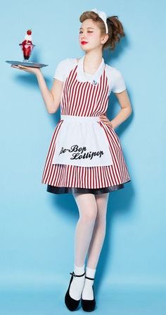 a woman in an apron holding a plate with a cupcake on it