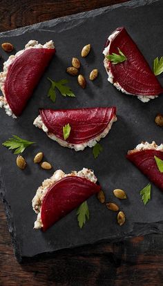 some food is laying out on a slate board with nuts and garnishes