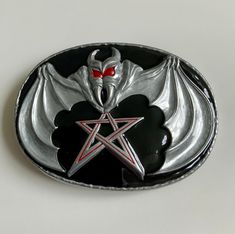 "vampire bat and pentagram oval belt buckle. Light gunmetal/ pewterplated, black shiny enamel background, red bat eyes and pentagram detailing.  This buckle is designed to fit an 1.5\"(38mm) belt strap. Solid , casted , detailed oval buckle featuring a flying vampire bat and pentagram. Plated in a thick , rich coating of pewter with a shiny black enamel background." Gothic Silver Oval Jewelry, Gothic Black Oval Jewelry, Black Oval Gothic Jewelry, Gothic Oval Collectible Jewelry, Bat Belt Buckle, Oval Belt, Bat Eyes, Vampire Bat, Vintage Belt Buckles