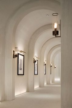 the hallway is lined with arches and framed pictures on the wall, along with two lamps