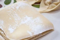 two folded napkins sitting next to each other on top of a white table cloth