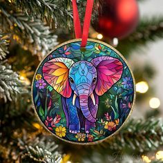 an ornament hanging on a christmas tree with flowers and an elephant painted on it