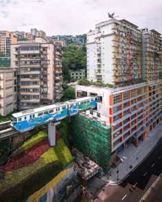 the train is going over the bridge in front of the building with many windows and balconies