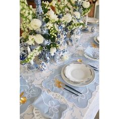 the table is set with blue and white dishes, silverware, and floral centerpieces