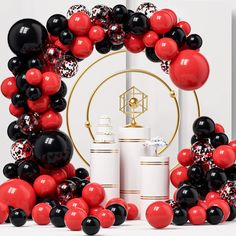 black, red and white balloons in front of a gold stand with gifts on it