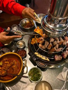 a person is serving food from a large pot on top of a table with other dishes and utensils